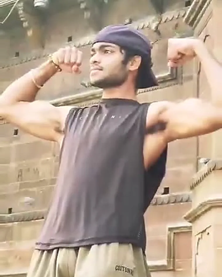 Coach Alok holding a double-biceps pose on the ghats in Varanasi
